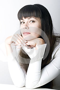 Young girl with bangs sitting behind the table photo