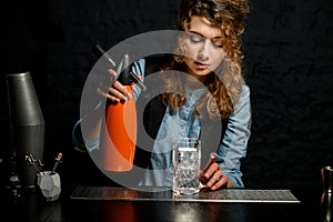 Young girl at bar holds orange siphon in her hand
