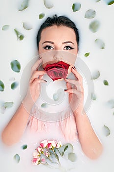 Young girl in bath with milk and rose petal