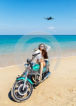 Young girl in a bathing suit on a beach with the motorcycle