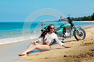 Young girl in a bathing suit on a beach with the motorcycle