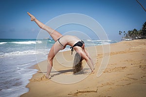 Young girl on the beach doing morning excercises