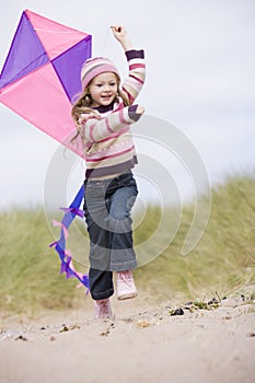 Young girl on beach with kite smiling