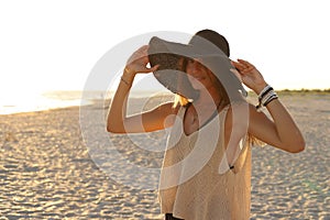 Young girl on the beach in a swimsuit, pareo, big straw hat