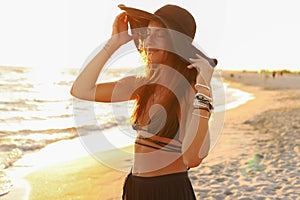 Young girl on the beach in a swimsuit, pareo, big straw hat