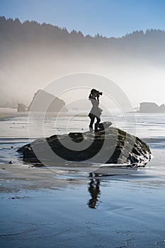 Young girl on beach taking photos of Oregon coast