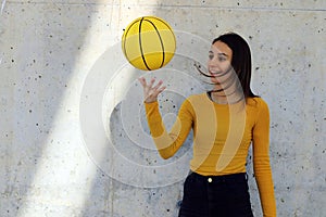 Young girl and beautiful basketball player dressed in yellow doing tricks with yellow basketball in an urban court