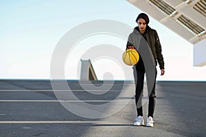Young girl and beautiful basketball player throwing yellow basketball in an urban court