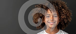 Young girl with beautiful curly hair happily smiling while making eye contact with the camera