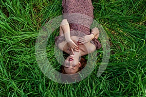 A young girl in a beautiful dress lies in the green grass