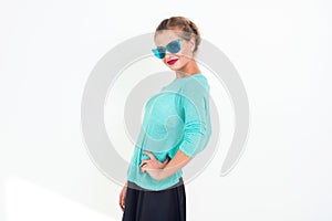 Young girl with a beautiful smile and stylish messy hairstyle wearing blue sunglasses, minty top, posing, standing