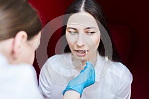 Young girl in the beauty parlor. Doctor humidifies lips gel. dentistry hygiene.