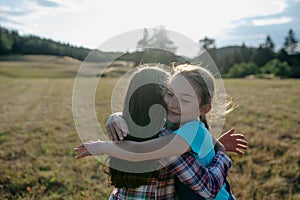 Young girl best friends spending time in nature, during sunset. Girls on walk, embracing.