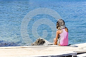 Young girl in bikini and headphones, listening to music on a pier