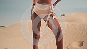 Young girl in a bikini stands barefoot on the sand