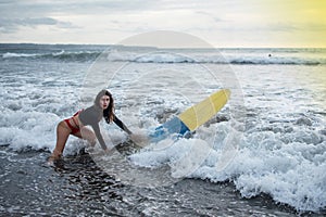 Young girl in bikini - surfer with white lines mask on her pretty face surf board dive underwater with fun under big