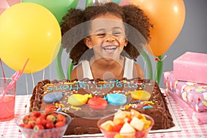 Young girl with birthday cake and gifts at party