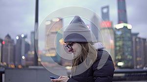 A young girl in a black jacket and hat slowly walks and rewrites by phone