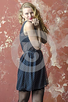 Young girl with blonde curly hair in a long dress with polka dots