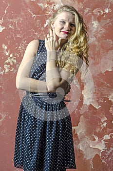 Young girl with blonde curly hair in a long dress with polka dots