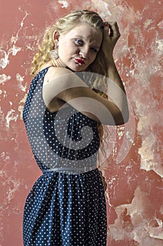 Young girl with blonde curly hair in a long dress with polka dots