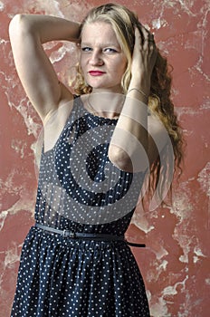 Young girl with blonde curly hair in a long dress with polka dots