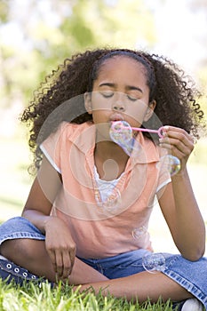 Young girl blowing bubbles outdoors