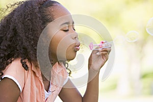 Young girl blowing bubbles outdoors