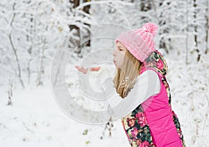 Young girl blows off snowflakes from palm