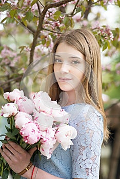 Young girl with a bouquet of peonies in the park, garden. Summer, spring