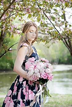 Young girl with a bouquet of peonies in the park, garden. Summer, spring