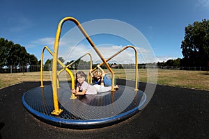 Young girl and boy playing on roundabout