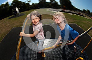 Young girl and boy playing on roundabout