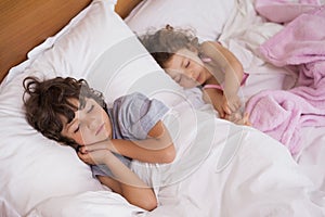 Young girl and boy sleeping in bed