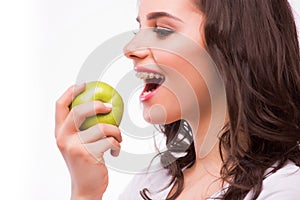 Young girl with brances eat apple. Female teeth with dental braces and apple.