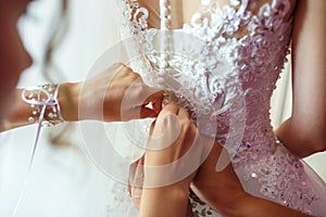 Young girl bride in wedding dress is waiting for the groom. girlfriend helps to fasten a dress