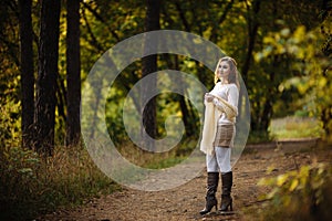 Young girl in bright clothes against a background of tree trunks in the autumn forest