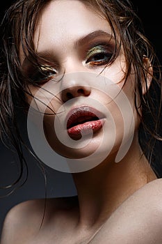 A young girl with bright creative makeup and perfect skin. Beautiful model with wet hair on face