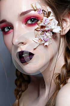 Young girl with bright pink creative make-up. Beautiful model with lips of the color of Marsala and application of flowers. Suspen