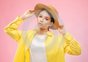 Young Girl in a bright yellow sweater and straw hat, she has a beautiful bright make-up