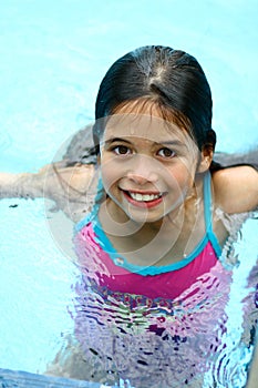 A young girl with brown eyes enjoys being in the swimming pool
