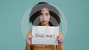 Young girl with brunette, frizzy hair holding a Stop war banner