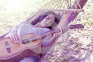 Young girl, brunette lies in a hammock with a guitar, toned