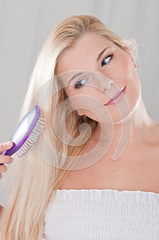 Young girl brushing long healthy hair