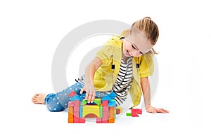 Young girl building a castle with wooden toy block. Child play therapy concept on white background.