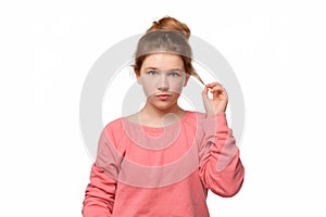 Young girl with bun hairstyle curling strand of hair on finger, looking thinking, having great plan