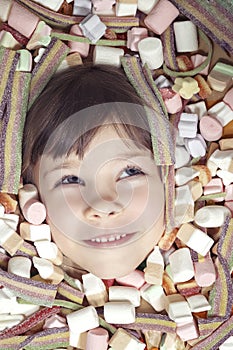 young girl buried on colorfull candies. candies, sweets, marshmallows,