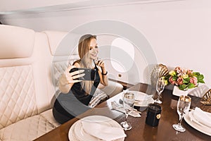 Young girl in the cabin of a business class airplane with a phone in her hands comfortable luxury travel