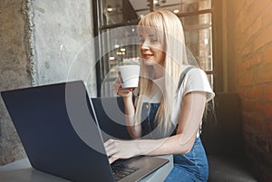 Young girl at cafe drinking coffee and using mobile phone. Online shopping