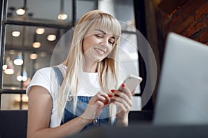 Young girl at cafe drinking coffee and using mobile phone. Online shopping